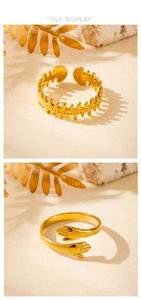 Detail display of golden zigzag band and embrace hands ring on sandy textured surface