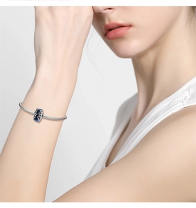 Detail of silver snake chain bracelet with deep blue rectangle glass bead charm on wrist