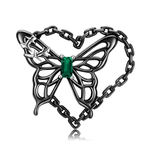 Macro detail of butterfly pendant with green gemstone in a heart-shaped chain frame