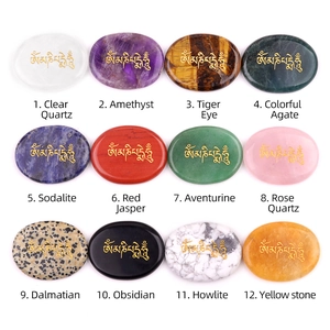 Twelve natural gemstone worry stones with gold Om Mani Padme Hum engraving on white background