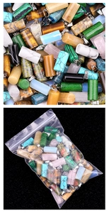 Macro shot of assorted cylindrical stone pendants with silver bails in retail packaging