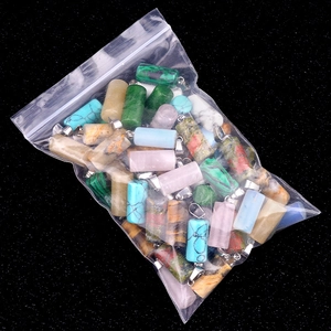 Assorted cylindrical natural crystal pendants with silver metal clasps in bulk packaging