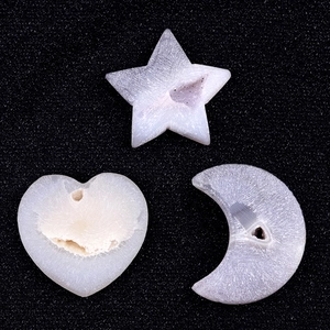 Natural crystal agate carvings in star, heart, and crescent moon shapes on dark background