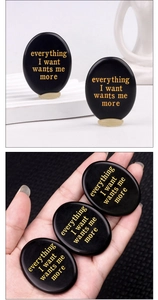 Macro detail of polished black obsidian thumb stone with gold engraved text for meditation