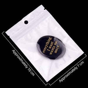 Black oval obsidian palm stone with golden inspirational text in transparent retail packaging