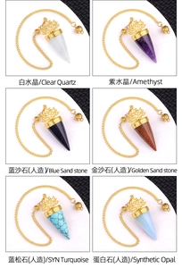 Detail view of various crystal dowsing pendulums with golden lotus metal caps and chains