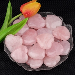 Polished natural pink rose quartz heart stones in a glass bowl for home decor