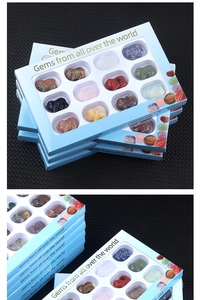 Macro view of 12 gemstone pig carvings in a blue window gift box on a black textured surface
