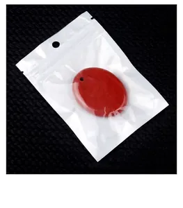 Detail shot of a red oval crystal stone pendant inside a white and clear retail polybag