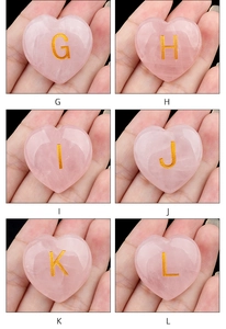 Makro-Detail von Herzsteinen aus rosa Rosenquarz mit goldgravierten Buchstaben G bis L