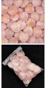 Makroaufnahme von herzförmigen Rosa Quarzsteinen mit gravierten goldenen Buchstaben
