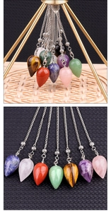 Macro detail of teardrop crystal pendants hanging from a gold pyramid stand for meditation