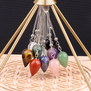 Water drop crystal dowsing pendulums with silver chains on a gold pyramid stand