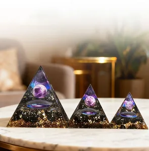 Three handmade resin crystal pyramids with gold foil and purple spheres on a marble table