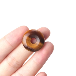Handheld natural tiger eye stone donut pendant with smooth polished finish and chatoyancy