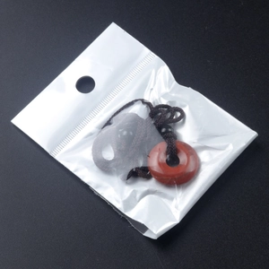 Pendentif donut en agate rouge avec cordon tressé présenté dans son sachet