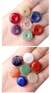 Macro view of seven natural chakra stone donut pendants held in hand for size context