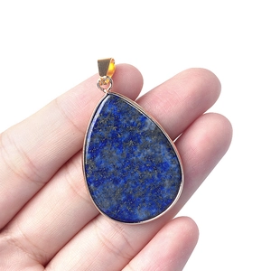 Lapis Lazuli teardrop pendant with gold-plated edging held by hand for scale