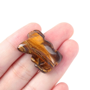 Handheld view of a carved tiger eye lizard figurine showing natural gold and brown textures
