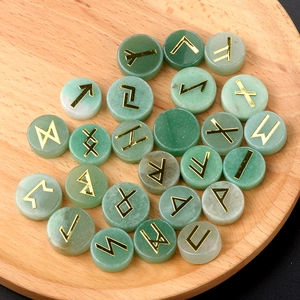 Natural green crystal Rune stone set with golden Norse engravings on a wooden tray