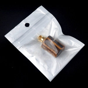 Parfümfles hanger van tijgeroog natuursteen met gouden dop in een verpakkingzakje
