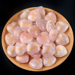 Natural rose quartz heart stones with gold engraved words in a round wooden tray