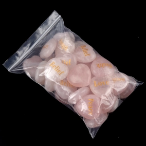 Natural pink quartz heart stones with gold engraved inspirational words on black backdrop