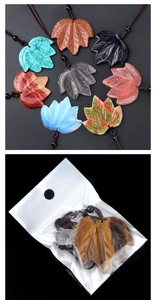 Macro detail of natural stone maple leaf pendants with hand-woven cord and leaf vein carving