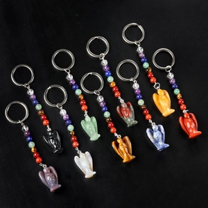 Porte-clés ange en pierre naturelle avec sept perles de chakra sur fond noir texturé