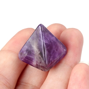 Polished natural amethyst pyramid crystal stone held in hand for energy decor