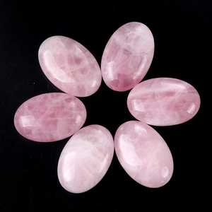 Natural pink quartz palm stones in soap shape for yoga and meditation on black background