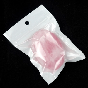 Natural pink quartz palm stone in soap shape for meditation shown in clear packaging