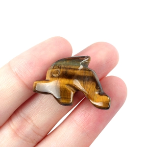 Polished tiger eye stone dolphin figurine carving held by hand for animal DIY projects