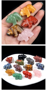 Macro detail showing hand holding small crystal bear carved from natural gemstones