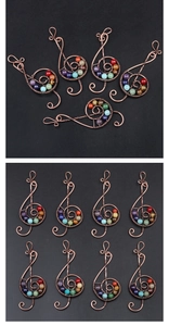 Macro detail of copper treble clef pendant with seven colorful chakra stones and wire wrap
