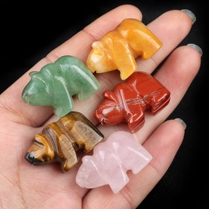Set of five carved natural gemstone polar bear figurines held in hand against black background