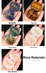 Détail de pierres de paume naturelles tenues en main avec des mots inspirants gravés en or