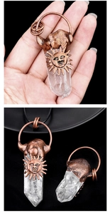 Macro shot of white crystal column pendant with vintage sun face metalwork and black cord