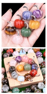 Macro shot of colorful mini gemstone pumpkin charms with metal hooks on wooden surface