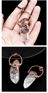 Détail d'un pendentif en cristal blanc bohème avec lune et étoile en bronze tenu en main