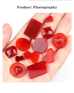 Red agate gemstones in various shapes held in hand showing texture and scale