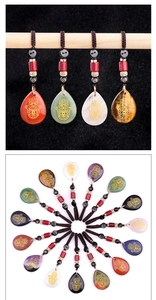Macro view of natural stone Hamsa Hand pendants with engraved gold totems and woven ropes