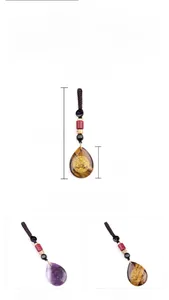Macro detail of teardrop gemstones with golden tree of life symbols on braided cord