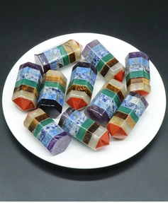 Polished seven chakra energy stones in hexagonal tower shape on a white round tray