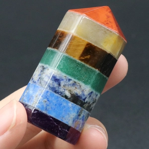 Polished natural seven chakra crystal hexagonal point tower held in hand for display