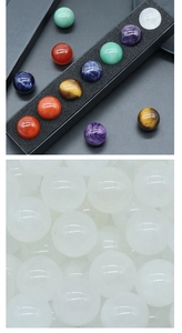Close-up of seven natural chakra crystal spheres neatly arranged in a black display tray
