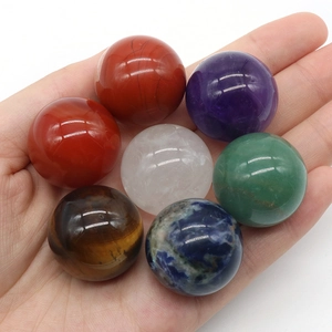 Set of seven natural chakra crystal spheres held in hand showing size and polished texture