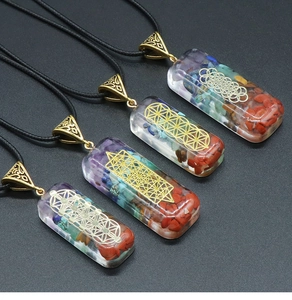 Détail de quatre pendentifs rectangulaires en résine avec pierres de chakra et symboles