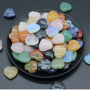 Close-up of polished colorful natural crystal heart stones on a matte black plate