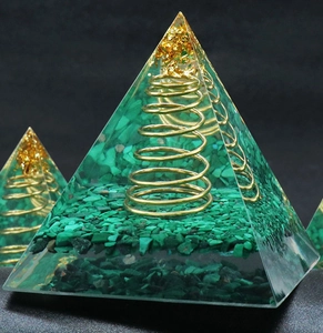 Macro shot of malachite resin pyramid with gold foil and copper spiral energy coil